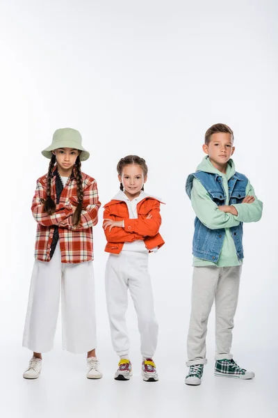 Longitud completa de niño y chicas con estilo de pie con brazos cruzados en blanco - foto de stock