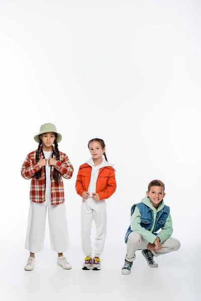 Full length of stylish boy and girls posing on white — Stock Photo