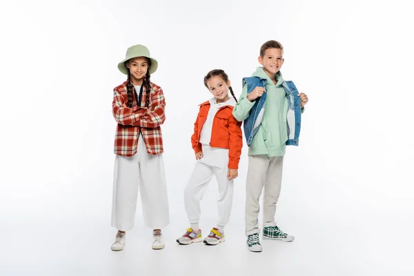 Full length of cheerful boy and smiling girls posing on white — Stock Photo