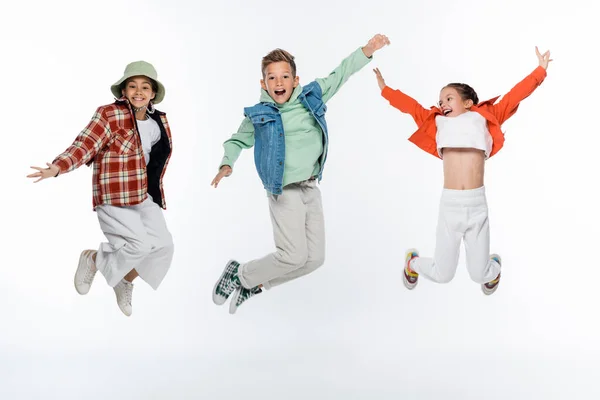 Comprimento total de crianças elegantes sorrindo enquanto levita em branco — Fotografia de Stock
