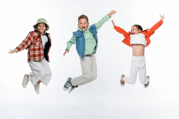 Toute la longueur des enfants élégants souriant tout en lévitant sur blanc — Photo de stock