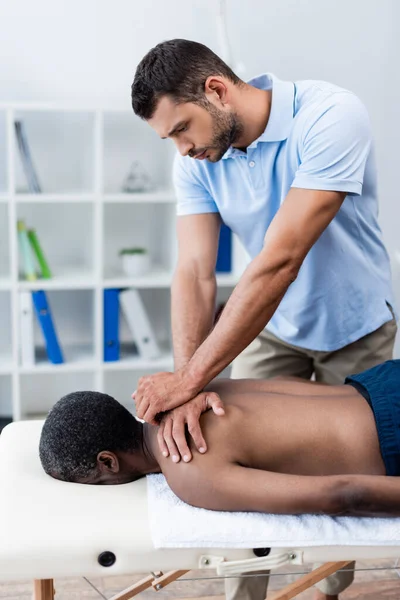 Afro-américain se faire masser le dos pendant la réadaptation physique — Photo de stock