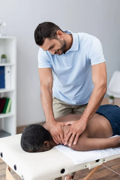 Homme afro-américain se faire masser les épaules dans le centre de réadaptation — Photo de stock