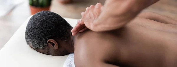 Paciente afroamericano recibiendo masaje de espalda durante el procedimiento de rehabilitación, pancarta - foto de stock
