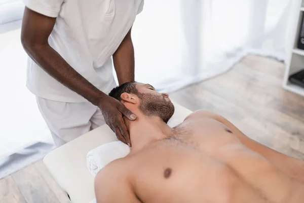 African american chiropractor treating young man in rehabilitation center — Stock Photo
