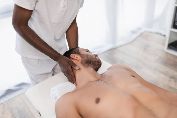 African american chiropractor treating young man in rehabilitation center — Fotografia de Stock