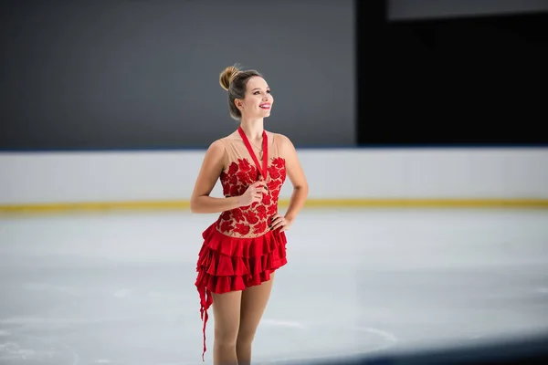 Patinador figura positivo em vestido vermelho segurando medalha de ouro e posando com a mão no quadril — Fotografia de Stock