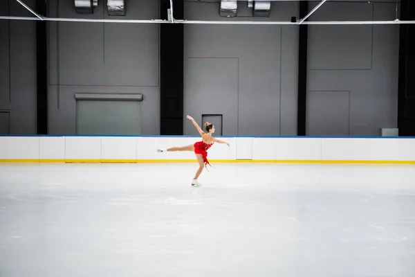 Toute la longueur du patineur artistique en robe effectuant chameau spin dans l'arène de glace professionnelle — Photo de stock