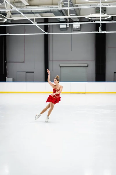 Piena lunghezza di giovane donna pattinaggio artistico e gesti in arena di ghiaccio professionale — Foto stock