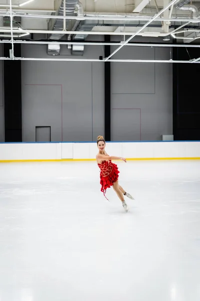 Full length of joyful young woman figure skating in professional ice arena — Foto stock