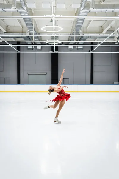 Full length of young woman bending while figure skating in professional ice arena — Foto stock