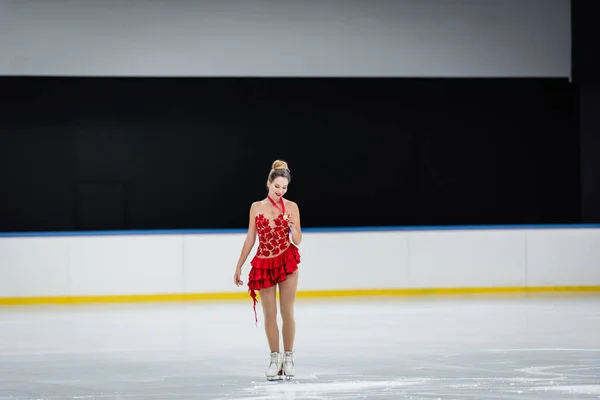 Full length of happy woman looking at medal in professional ice arena — Stockfoto