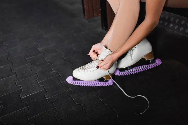 Recortado vista de la joven mujer atando zapatos de patinaje artístico - foto de stock