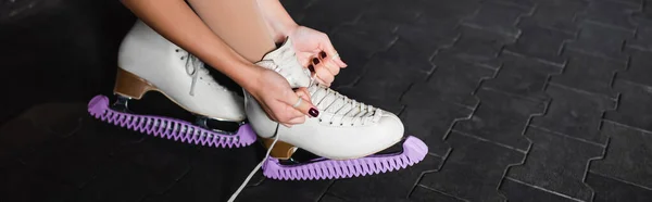 Cropped view of young woman tying figure skating shoes, banner — Stockfoto