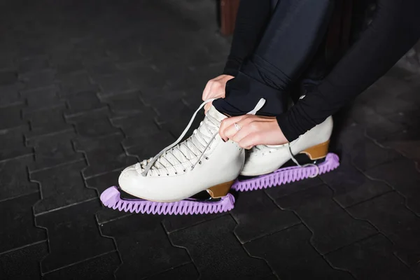 Jeune femme attacher des chaussures de patinage artistique tout en étant assis sur le banc — Photo de stock