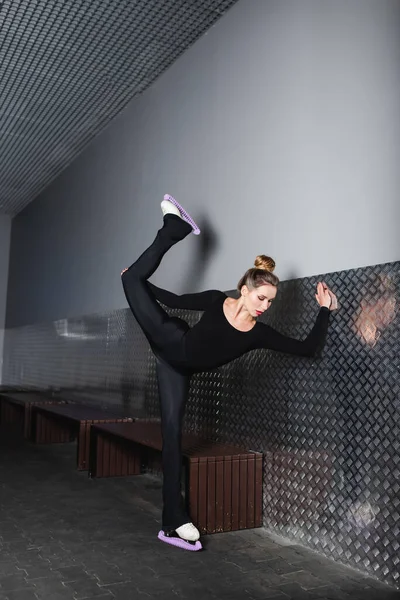 Junge Frau in Eiskunstläufen streckt sich nahe der Wand — Stockfoto