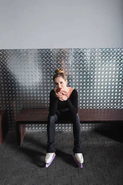 Pleine longueur de femme heureuse en patins à roues longues blancs et body noir assis sur le banc — Photo de stock