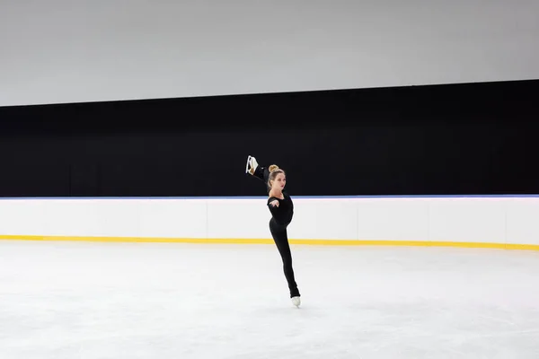 Comprimento total do patinador artístico em macacão preto patinando na arena de gelo congelado — Fotografia de Stock