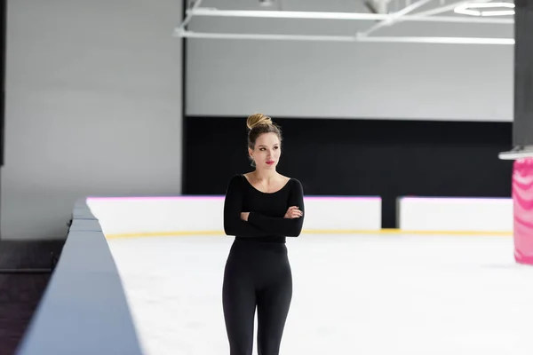 Jeune patineuse artistique en body noir posant avec les bras croisés — Photo de stock