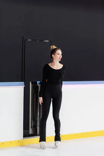Toute la longueur du jeune patineur artistique en body debout sur une patinoire gelée — Photo de stock