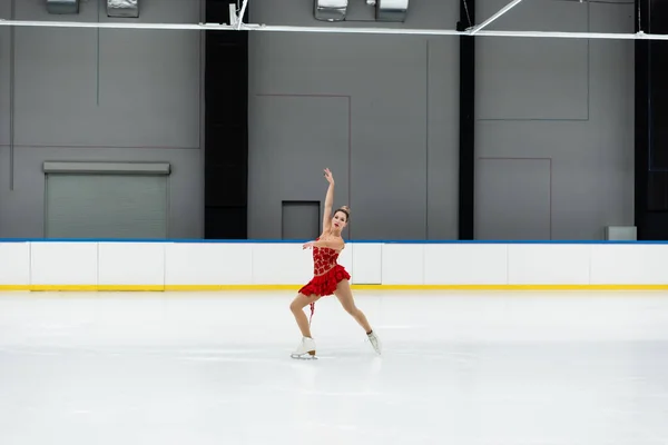 Full length of young woman in dress figure performing dance in professional ice arena — Stockfoto