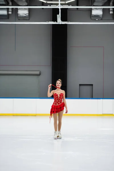 Comprimento total de patinador figura alegre em vestido vermelho mostrando medalha de ouro na pista de gelo — Fotografia de Stock