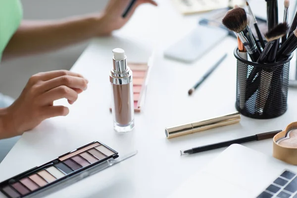 Cropped view of decorative cosmetics near blurred laptop and african american woman — Fotografia de Stock