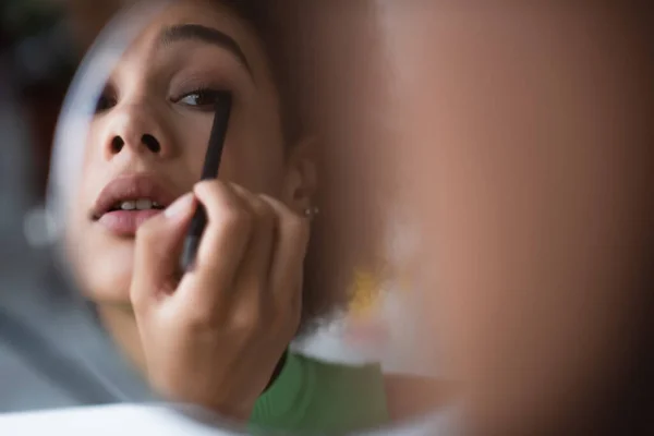 Africano americano mulher aplicando eyeliner perto do espelho — Fotografia de Stock