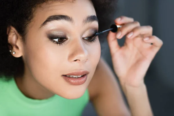 Femme afro-américaine appliquant mascara à la maison — Photo de stock