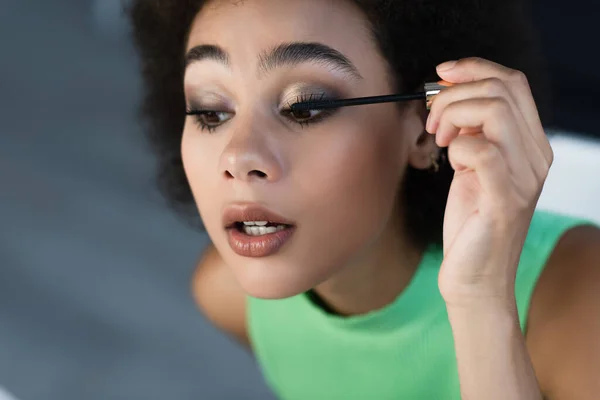 Jolie femme afro-américaine appliquant le mascara à la maison — Photo de stock