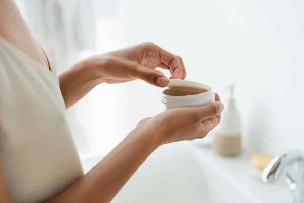 Vue recadrée d'une femme afro-américaine tenant un pot avec des patchs dans la salle de bain — Photo de stock