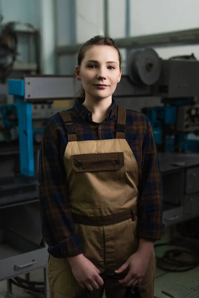 Young welder in overalls looking at camera in factory — Stockfoto