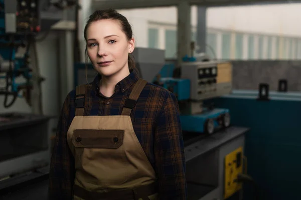 Young welder in uniform looking at camera in blurred factory — Foto stock