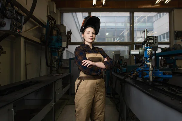 Welder in mask standing with crossed arms in factory — Stock Photo