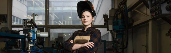 Welder in overalls and mask crossing arms in factory, banner — Stockfoto