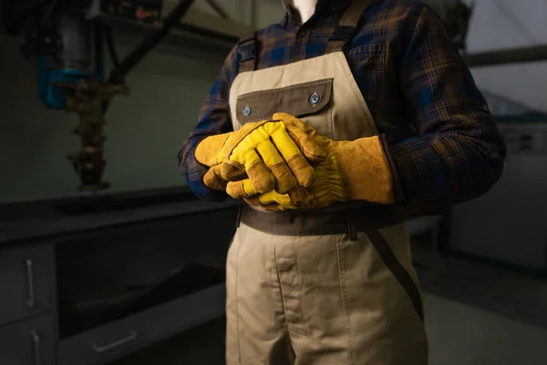 Cropped view of welder in gloves and overalls in factory — Stockfoto