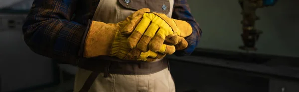 Обрізаний вид зварювальника в рукавичках, що стоять на заводі, банер — стокове фото