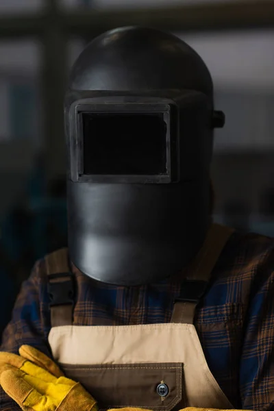 Welder in protective mask and overalls standing in factory — Stock Photo