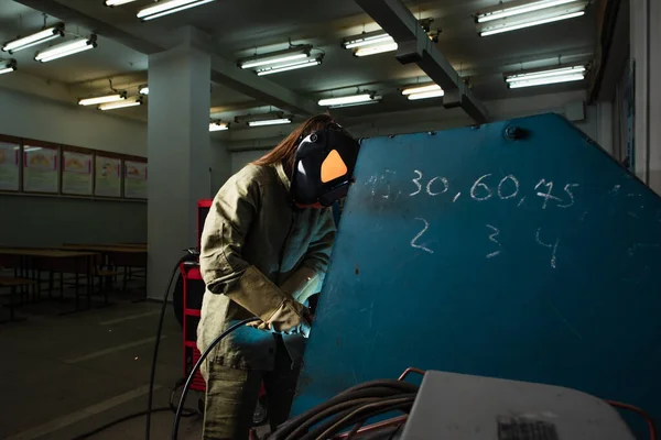 Сварщик в защитном шлеме работает на заводе — стоковое фото