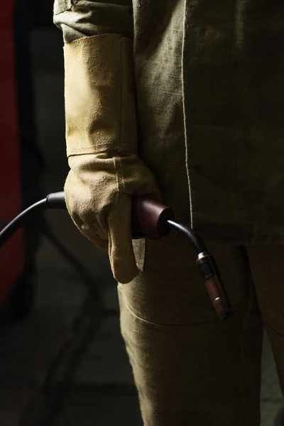 Vue recadrée du soudeur en gant et uniforme tenant torche de soudage dans l'usine — Photo de stock