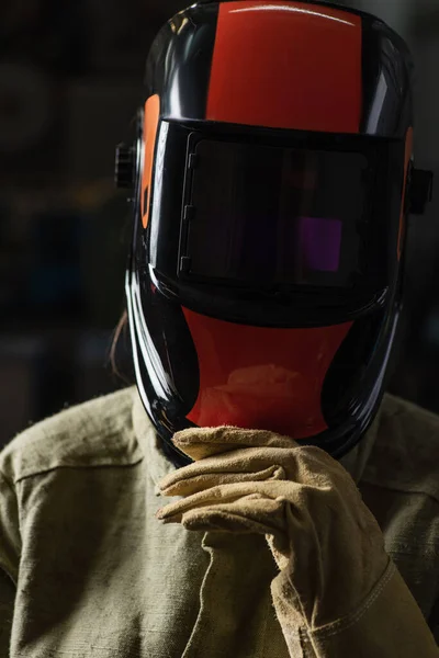 Soldador en uniforme que ajusta la máscara protectora mientras que está parado en fábrica - foto de stock