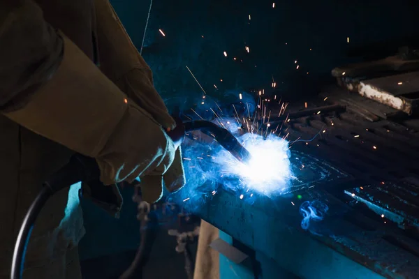 Vista recortada de soldador en guantes trabajando con antorcha en fábrica - foto de stock