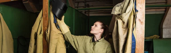 Welder taking protective mask in dressing room of factory, banner — Stock Photo