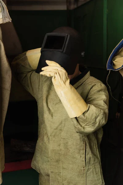 Welder in protective gloves wearing welding mask in factory — Stock Photo