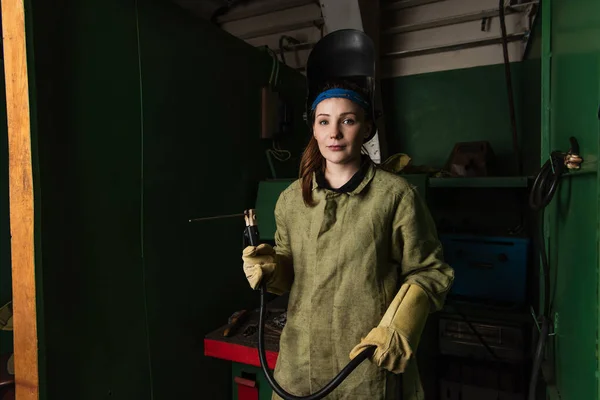 Young welder in uniform holding welding torch and looking at camera in factory — Stock Photo