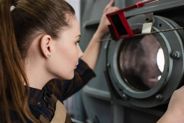 Side view of brunette welder working with vacuum laser welding machine in factory — Stockfoto