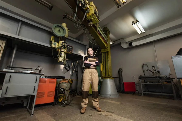 Welder looking at camera near machinery in factory — Stock Photo