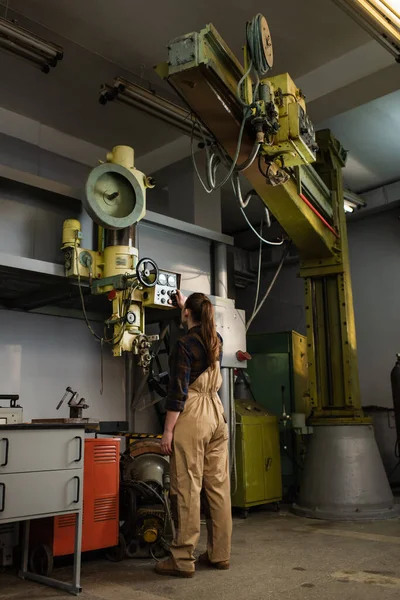 Young brunette welder tuning welding machine while working in factory — Stock Photo