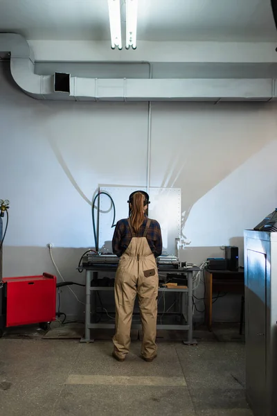 Back view of welder in mask and overalls working in factory — Stockfoto