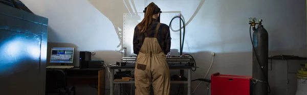 Back view of welder in overalls working near gas cylinder in factory, banner — Foto stock